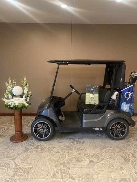 Golf ball urn and golf cart for display.